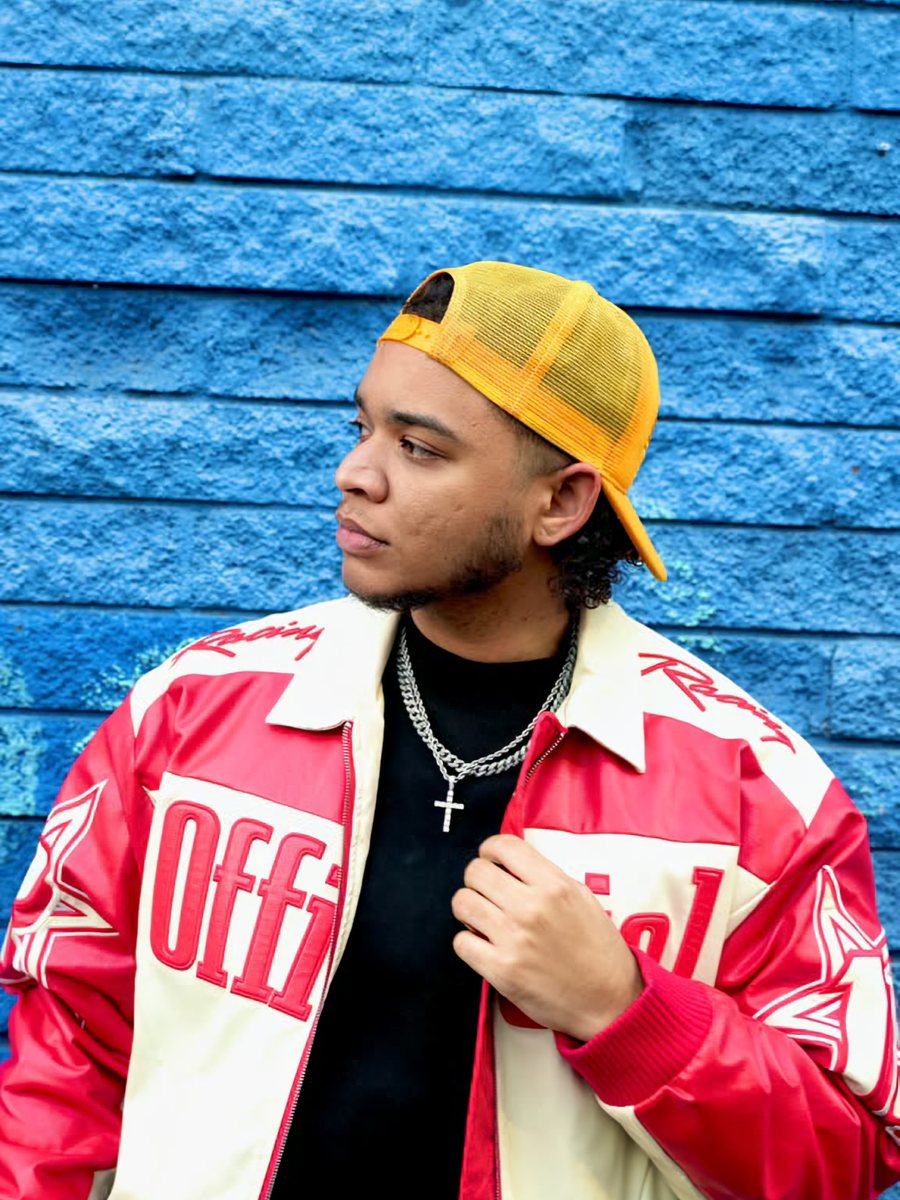 JBthePreacher in a yellow cap against a blue wall