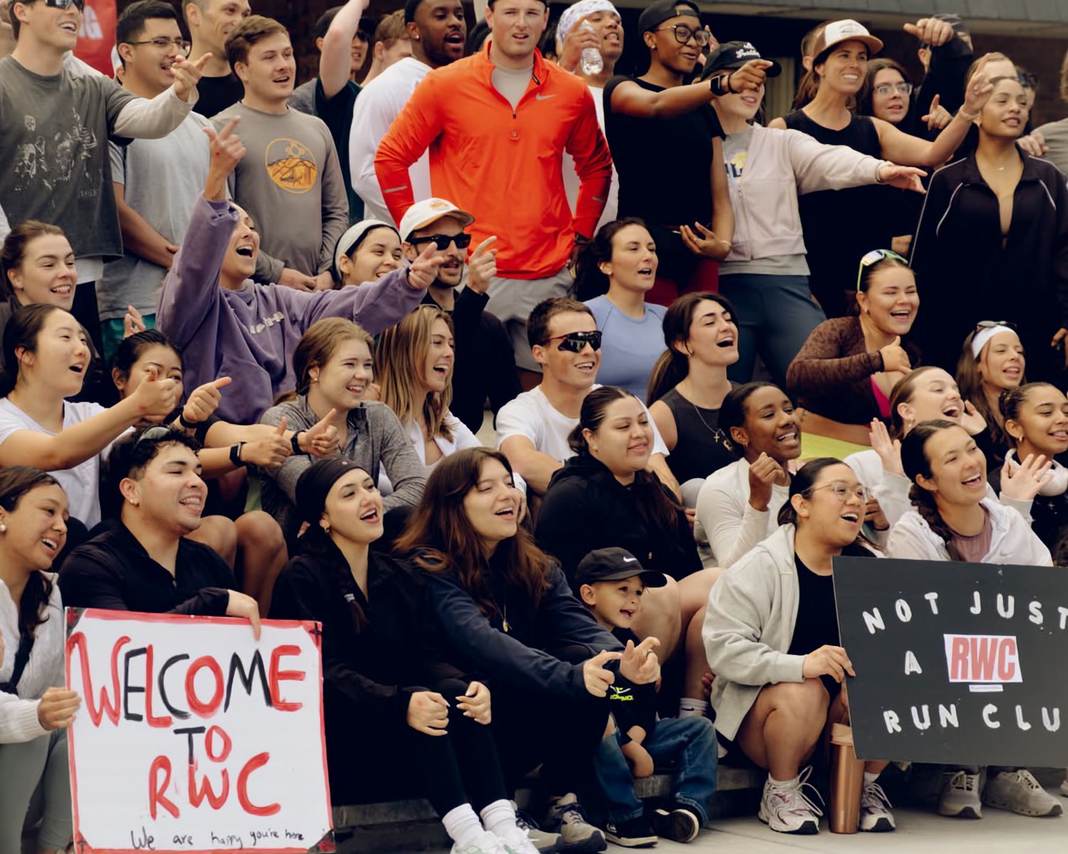 The RWC Denver crowd together after a run, holding a hand-painted Welcome to RWC sign