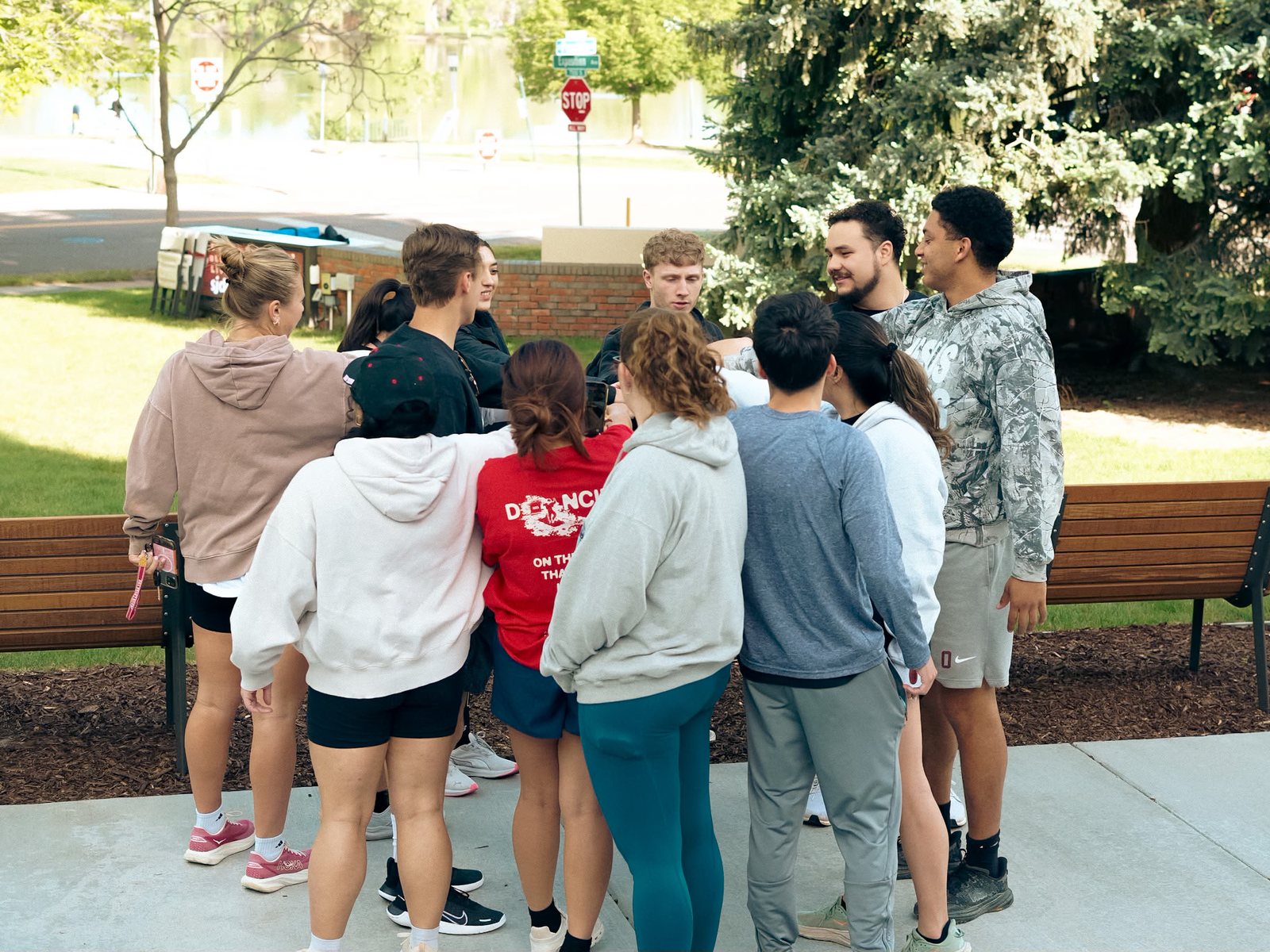 A circle of people huddled together in prayer on the grass at an RWC Denver event