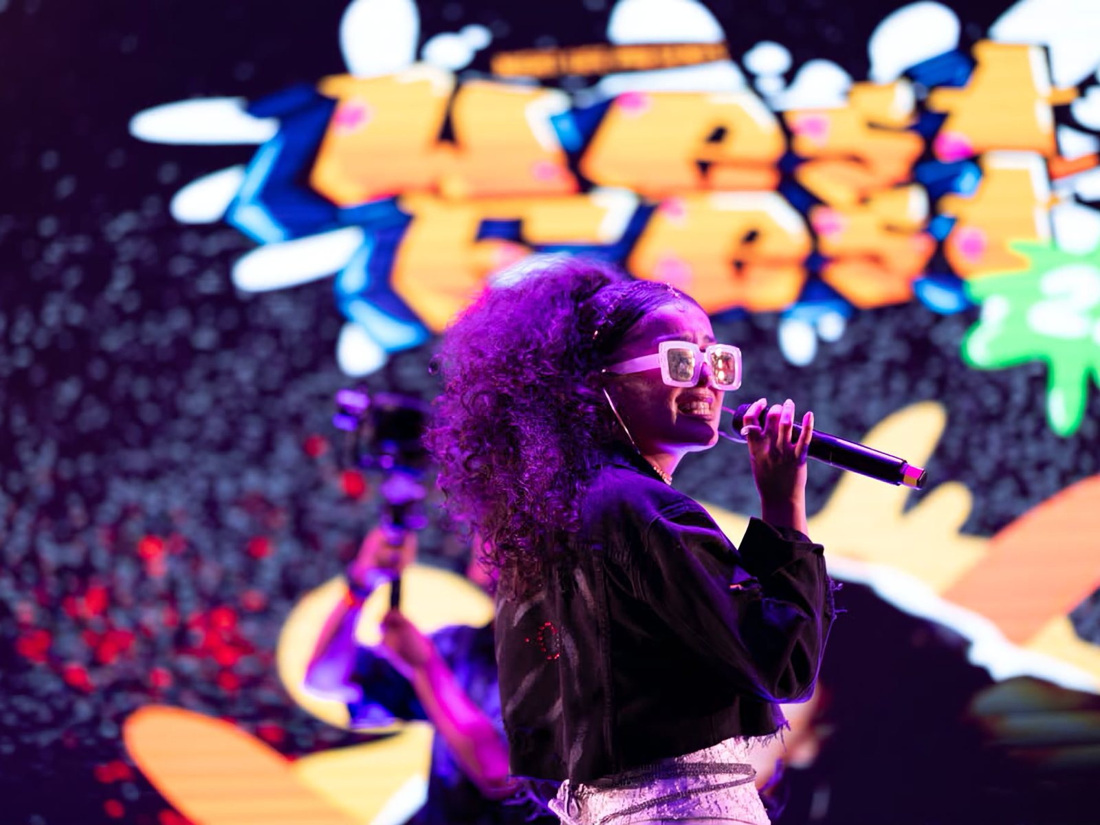 Petrina DeLacey performing under stage lights in front of a crowd