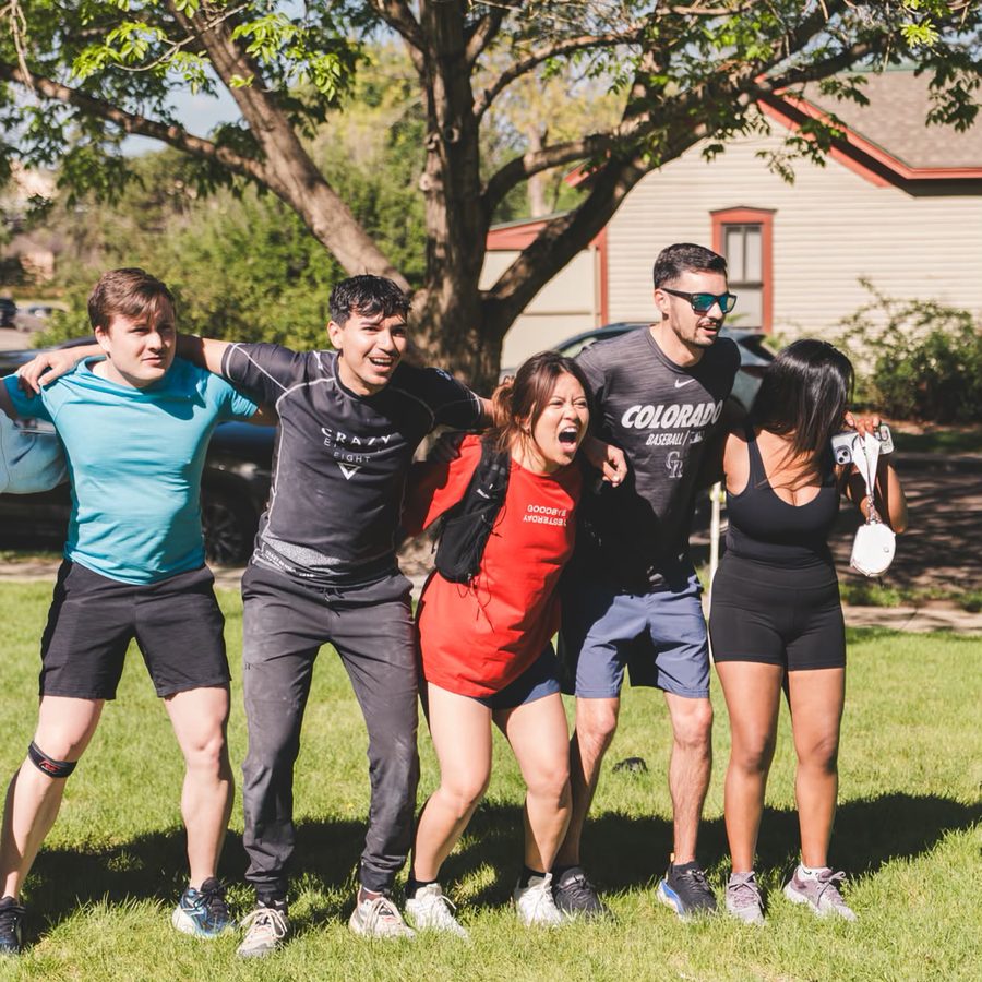 Five friends arm in arm on the grass after the run
