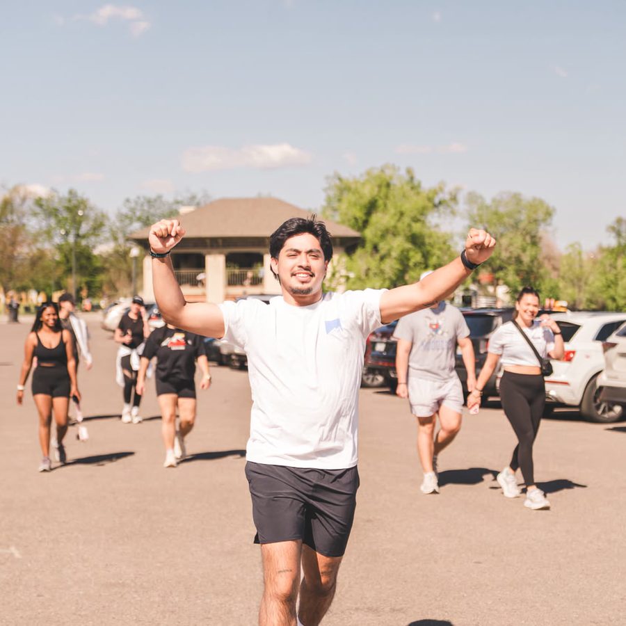 A runner throwing both arms up as he comes in