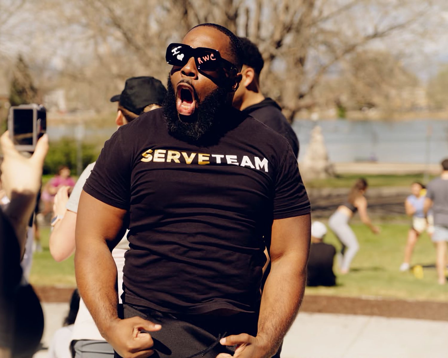An RWC Denver serve-team volunteer cheering runners on at the finish